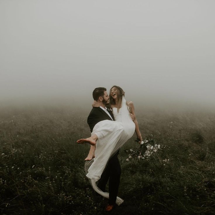 a man carrying a woman on his back in the middle of a foggy field