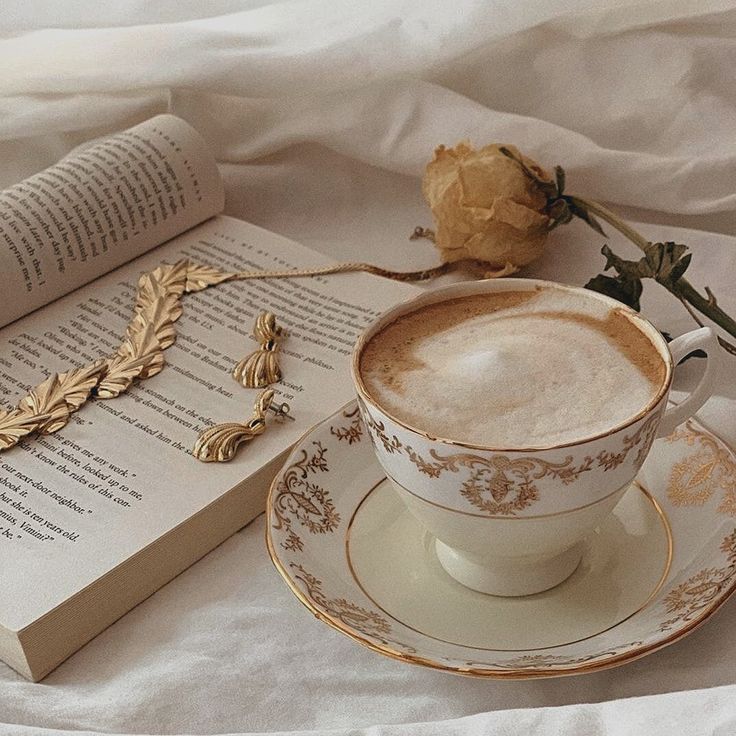 a cup of coffee sitting on top of a saucer next to an open book