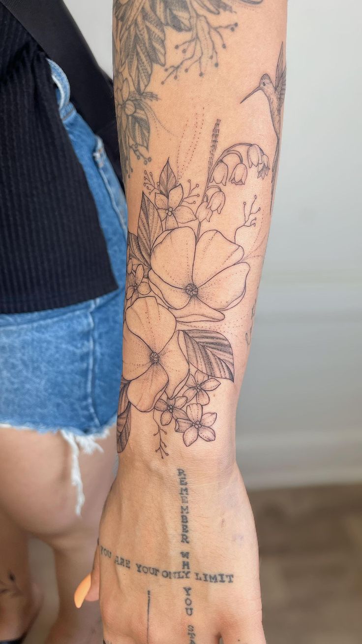 a woman's arm with tattoos on it and flowers in the middle of her hand