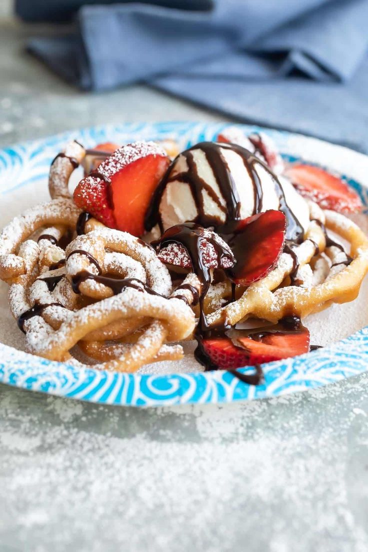 a blue and white plate topped with waffles covered in ice cream and strawberries