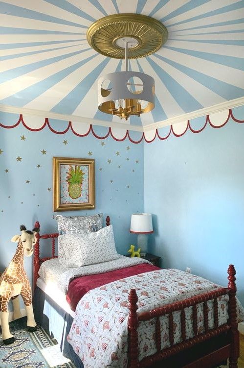 a bedroom decorated in blue and white with a striped ceiling fan above the bed, two stuffed animals on either side of the bed