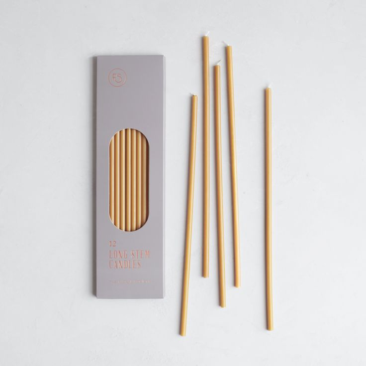 four bamboo chopsticks in a box next to each other on a white surface