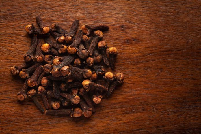 cloves are scattered on top of a wooden surface, including one in the center