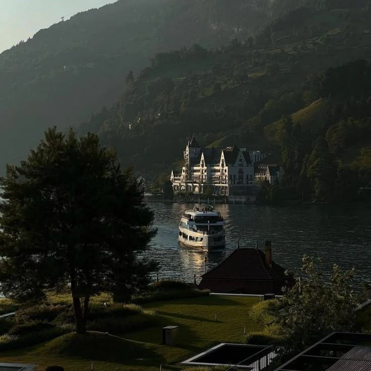 a boat is on the water in front of some houses and trees with mountains in the background