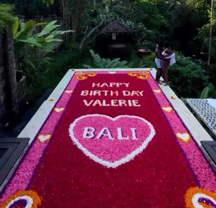 a woman standing on top of a red carpet covered in pink and orange flowers with the words happy birthday valerie written on it