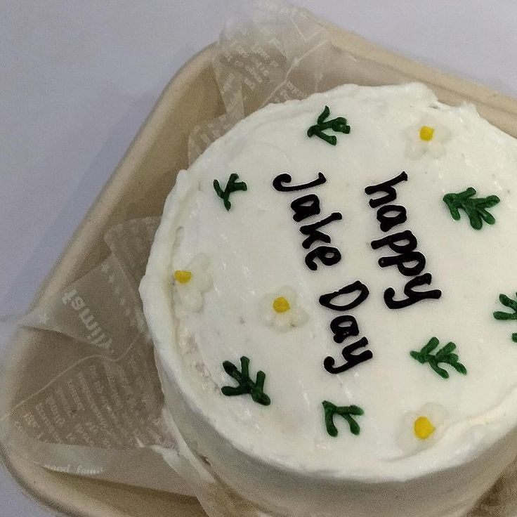 a birthday cake with white frosting and green leaves on it sitting on a plastic wrapper