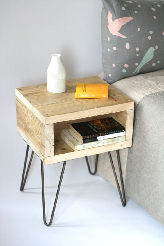 a table with some books on it next to a couch and pillows in a room