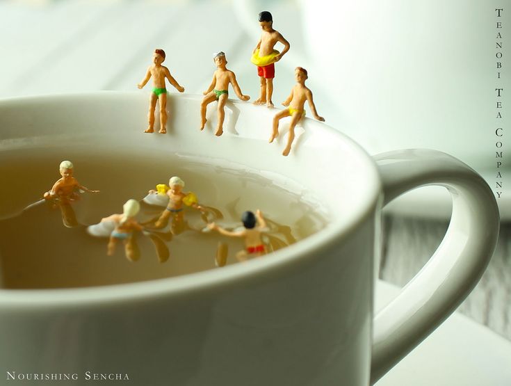 miniature people are floating in a cup of tea