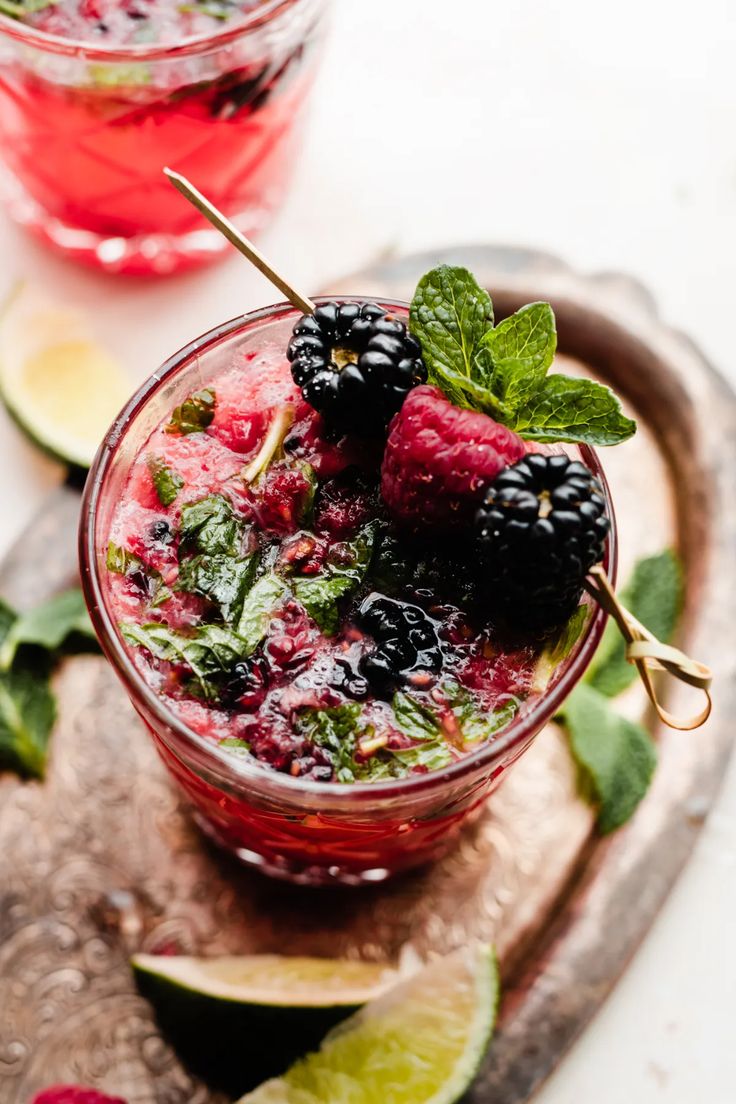 berries and mint garnish in a glass on a cutting board with limes