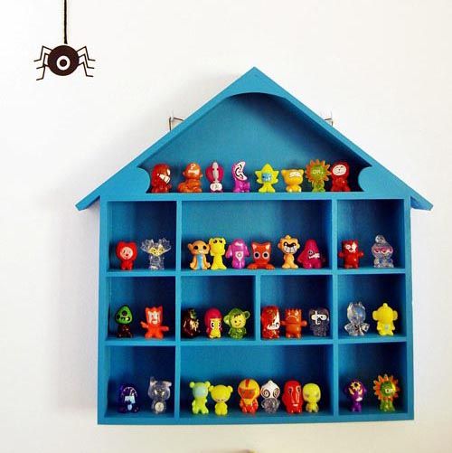 a blue shelf filled with toy figurines on top of a white wall