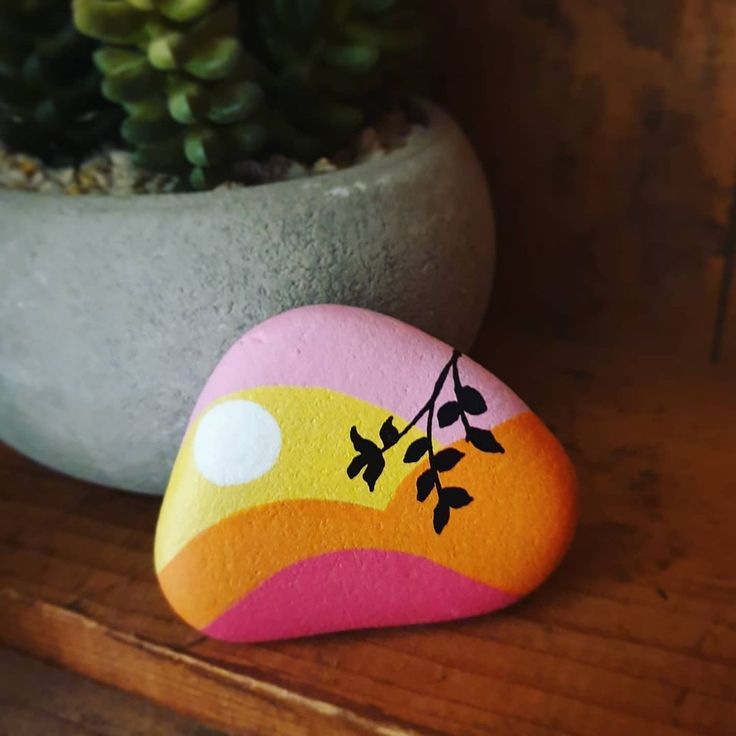 a painted rock sitting next to a potted plant