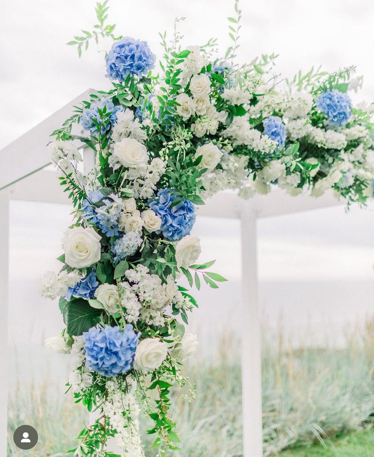 a white and blue floral arch with greenery