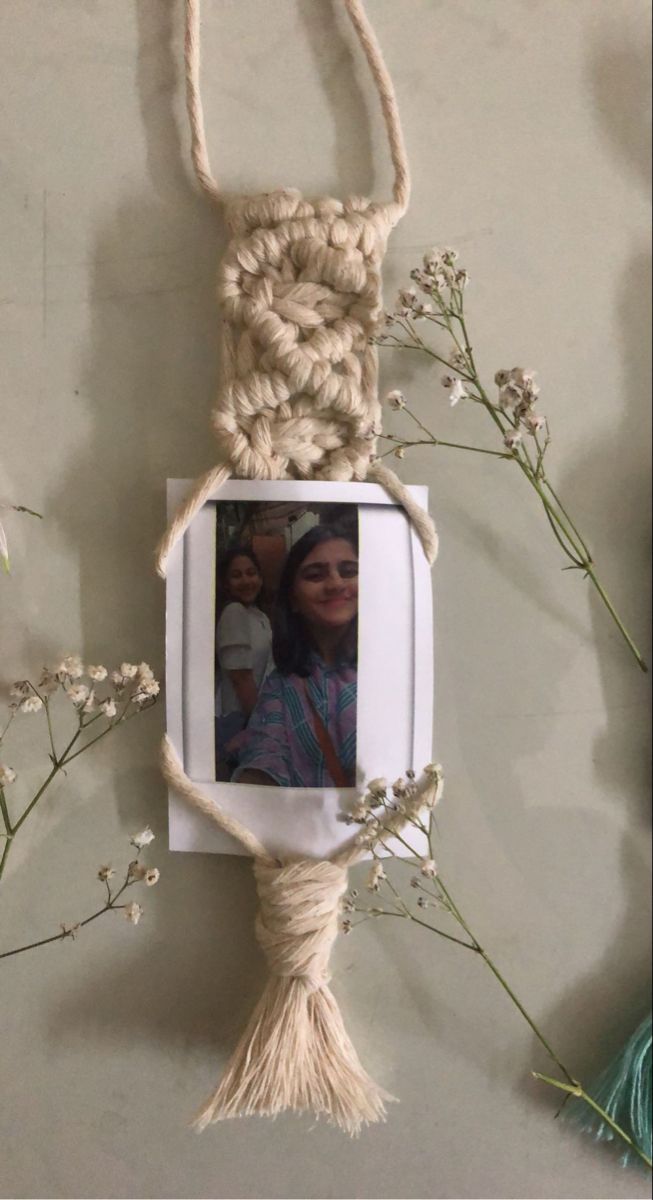 a photo hanging from a rope with flowers in front of it and an image on the side