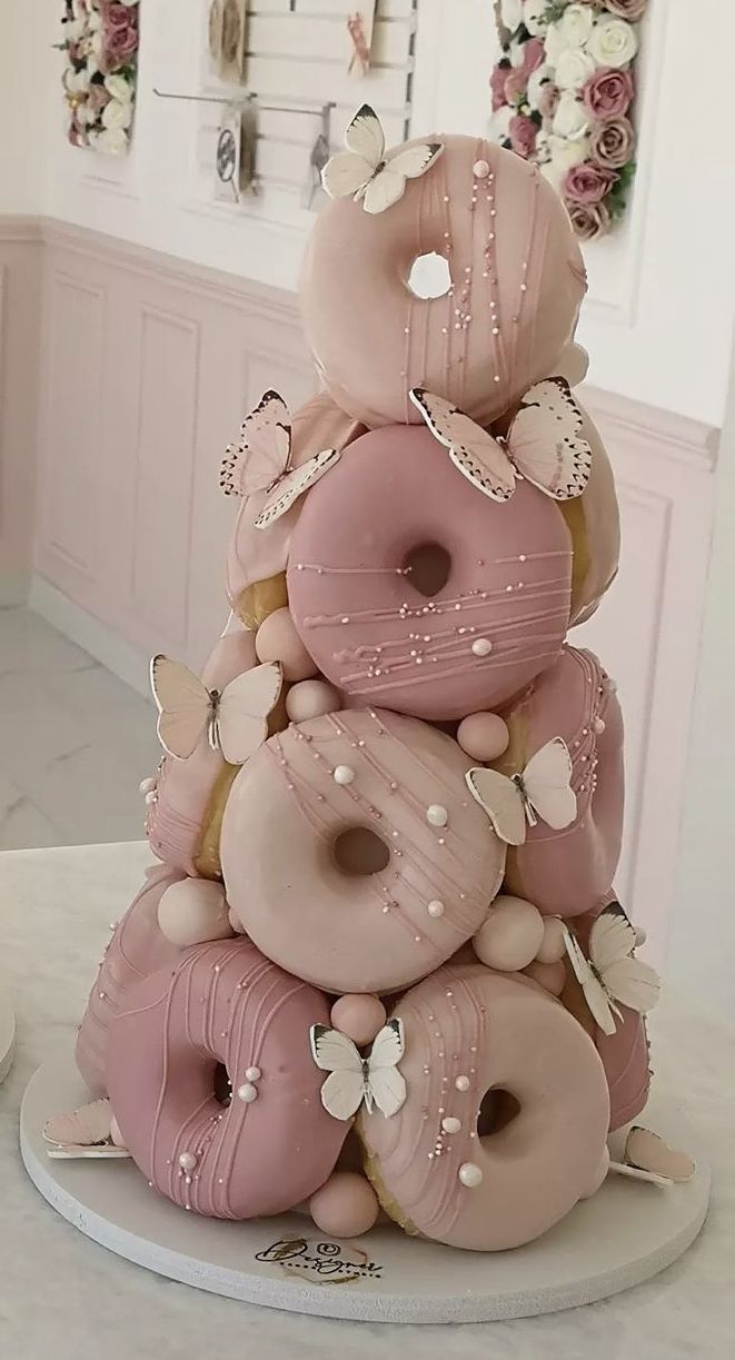 a large stack of doughnuts sitting on top of a white table in a room