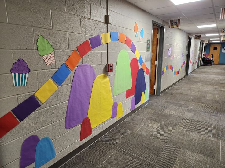 an office hallway decorated with colorful paper cutouts and cupcakes on the wall