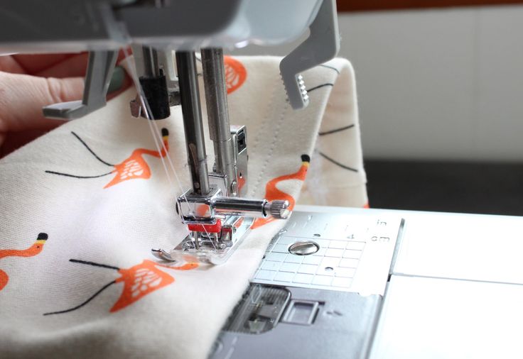 someone is using a sewing machine to sew something on a white cloth with orange foxes