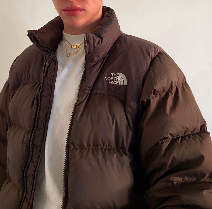 a woman wearing a brown jacket and white t - shirt with the north face logo on it