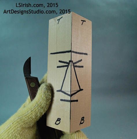 a hand holding a wooden block with a drawing on it and a pair of scissors in the other hand