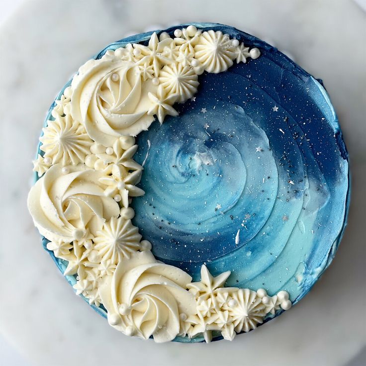 a blue cake with white frosting and stars in the middle on a marble surface