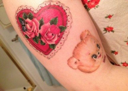 a woman's arm with a bear and heart tattoo on it