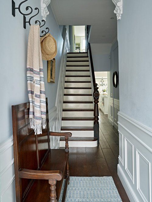 there is a wooden bench in front of the stairs and rugs on the floor