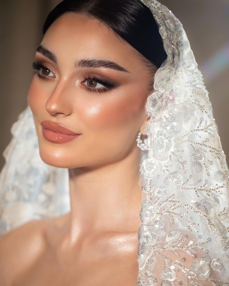 a woman wearing a veil and makeup looks into the distance while posing for a photo