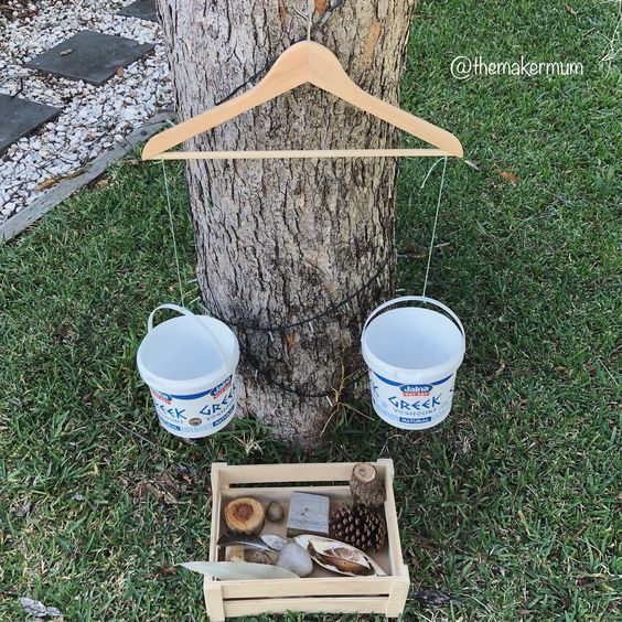 two buckets are hanging from a clothes hanger next to a tree with other items in it