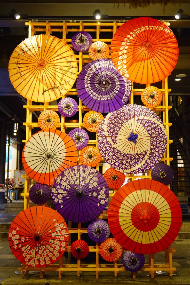 many colorful umbrellas are on display in a room with yellow scaffolding around them