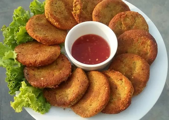 a white plate topped with fried food next to a bowl of ketchup and lettuce