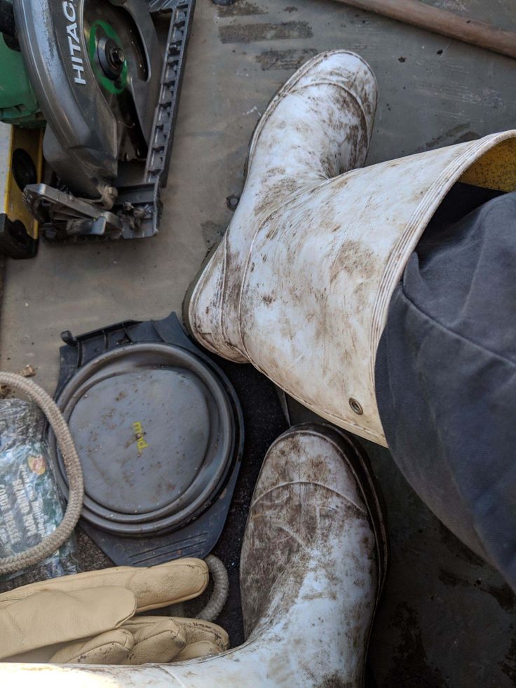 the bottom view of someone's shoes and their dirty boots are on the ground