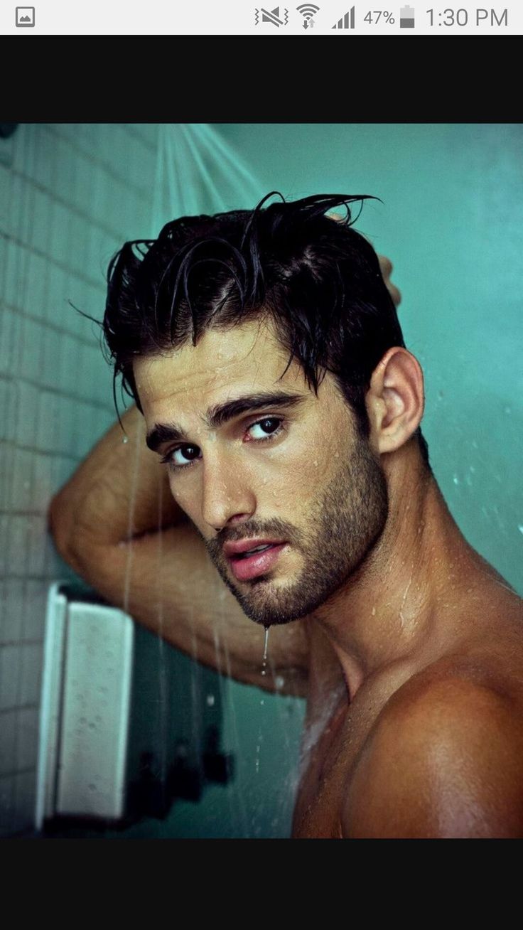 a shirtless man in the shower with his hand on his head looking at the camera