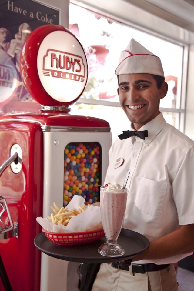 a man is holding a tray with food on it and a soda machine in the background