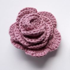 two crocheted pink flowers sitting next to each other on top of a white surface