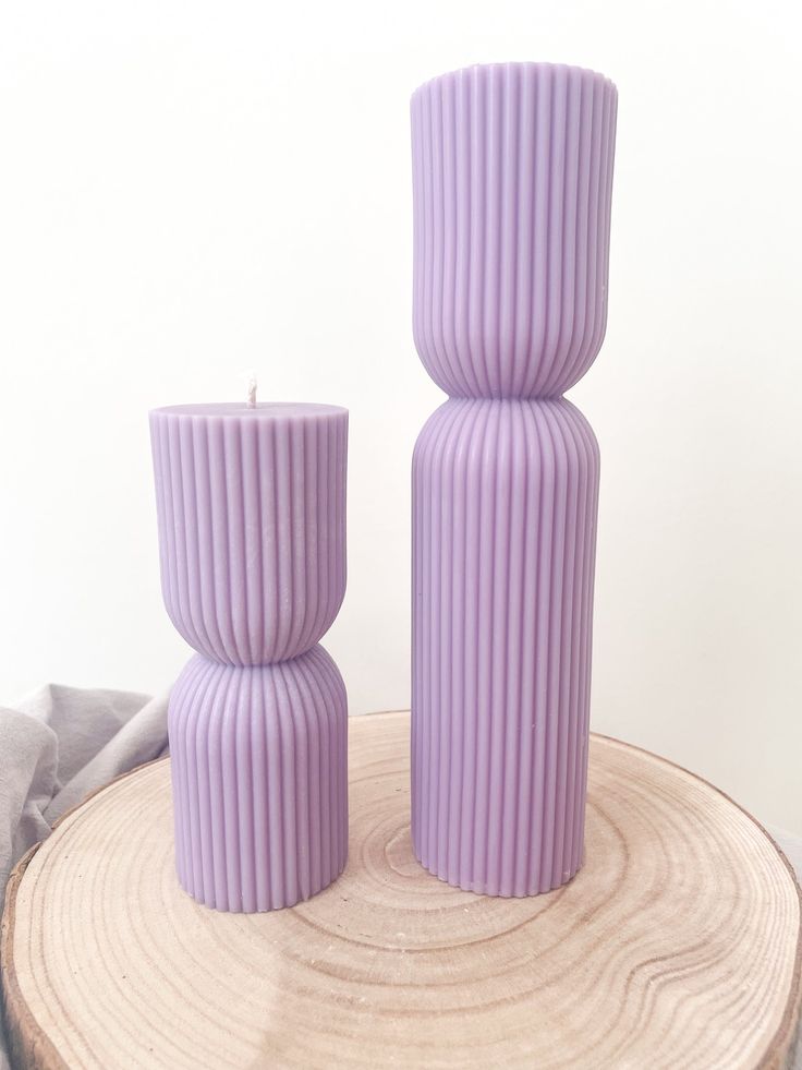 two purple vases sitting on top of a tree stump