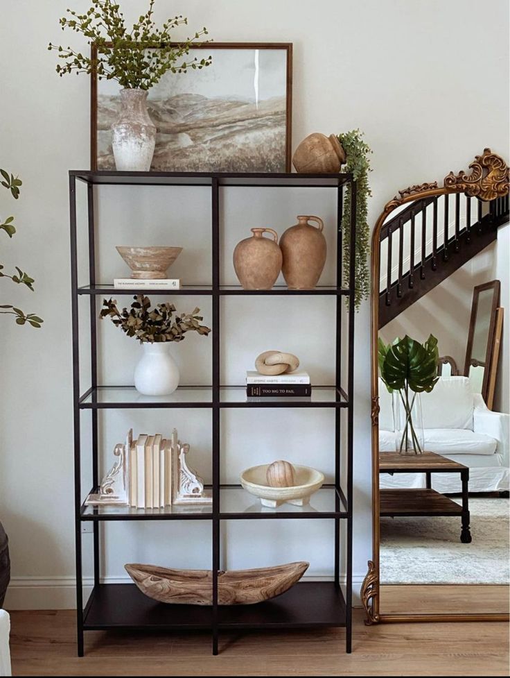 a bookshelf with vases and other items on it in a living room