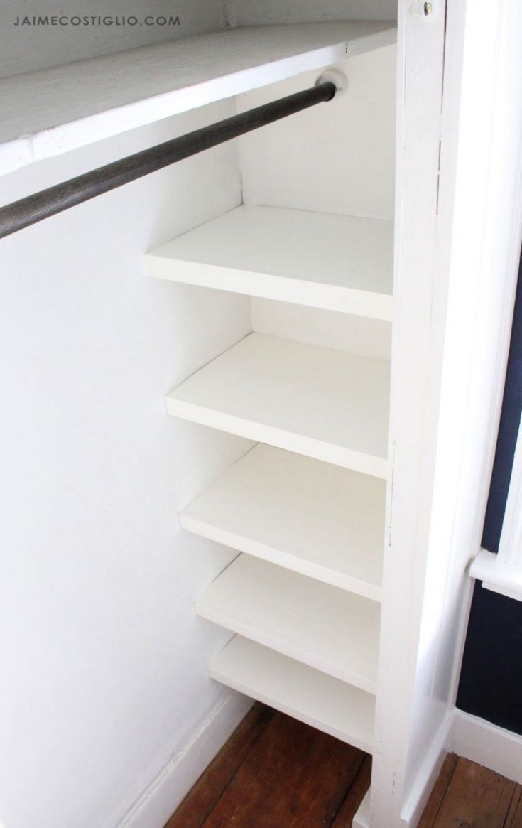 an empty closet with white shelves and wood flooring