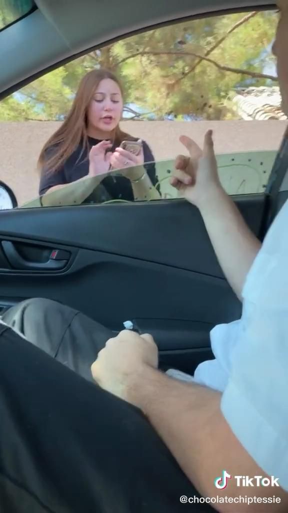 a woman sitting in the passenger seat of a car with her hand out to someone