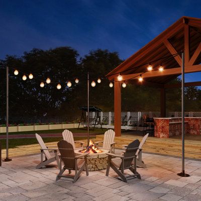 an outdoor fire pit surrounded by chairs and lights