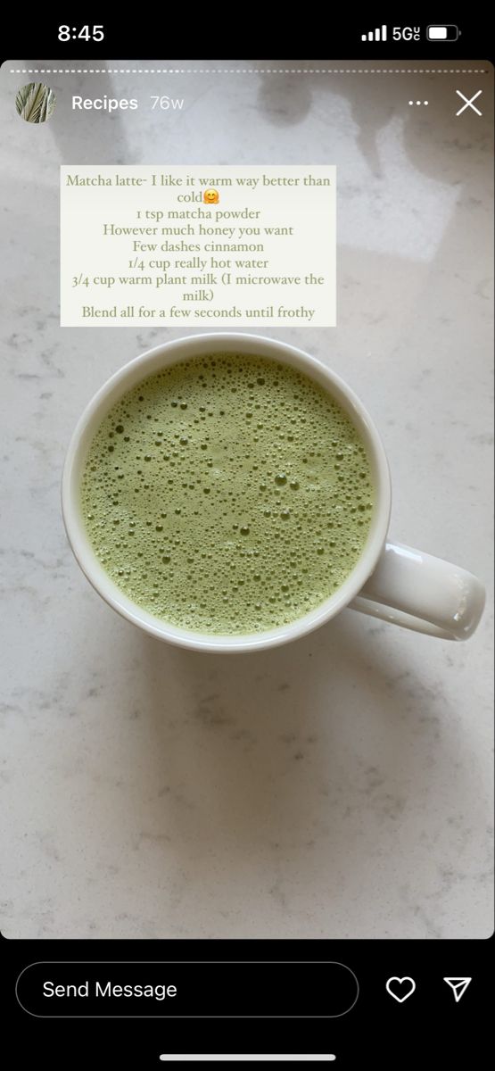 a cup of matcha latte on top of a white marble counter with a note in the middle