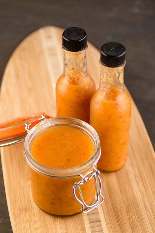 two jars of sauce sitting on top of a wooden board