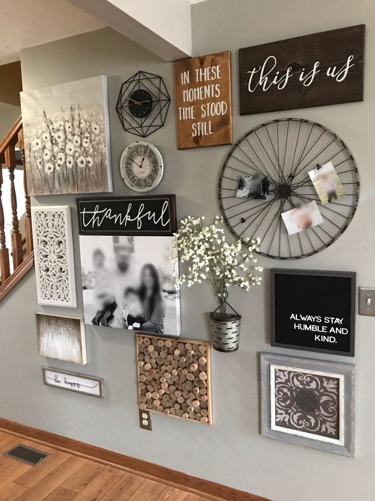 a wall with pictures, photos and other items hanging on it's side next to a stair case