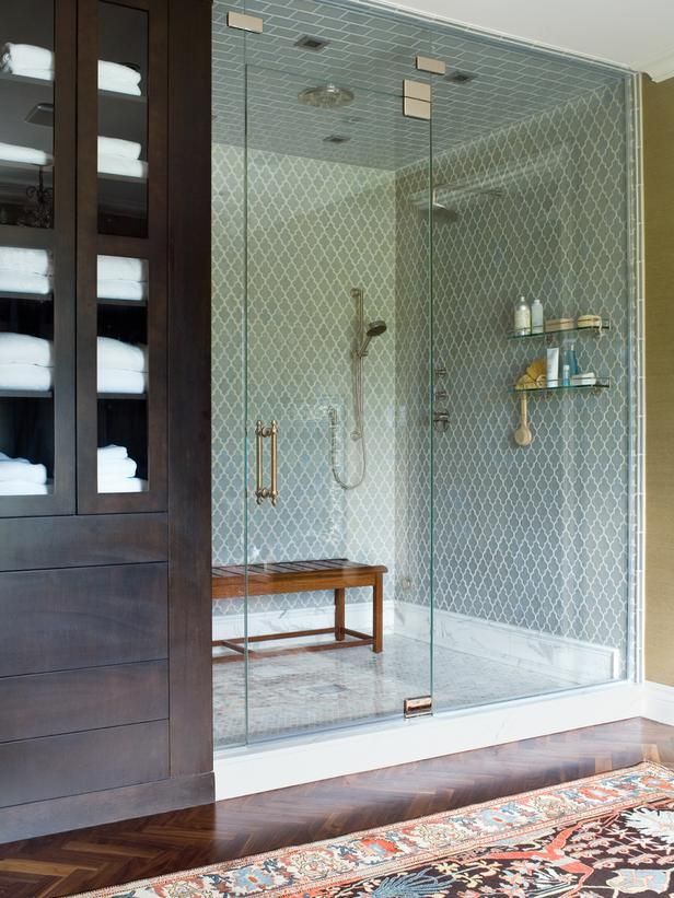 a walk in shower sitting next to a wooden door with glass panels on the doors