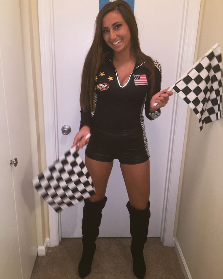 a woman is holding two checkered flags and posing for the camera while standing in front of a door