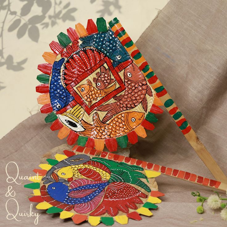 two colorful paper plates sitting on top of a table next to a flower pot and wooden stick