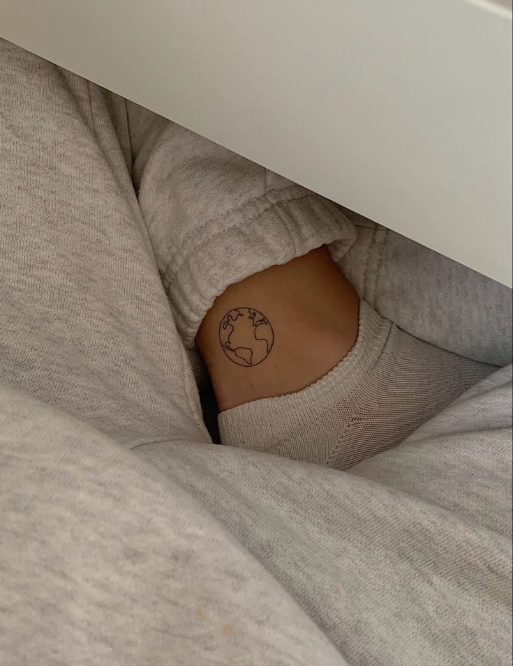 a person with a small tattoo on their stomach under a bed sheet and underneath the covers