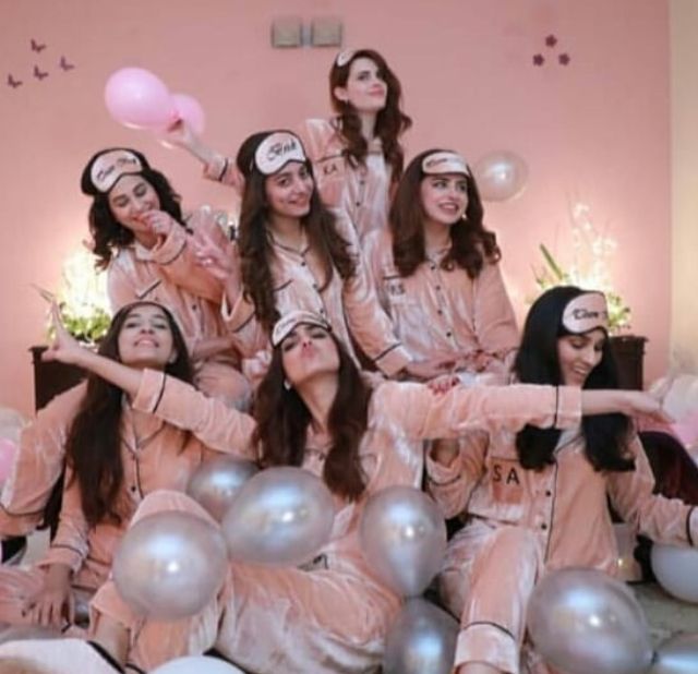 a group of women in pink pajamas posing for a photo with balloons and confetti