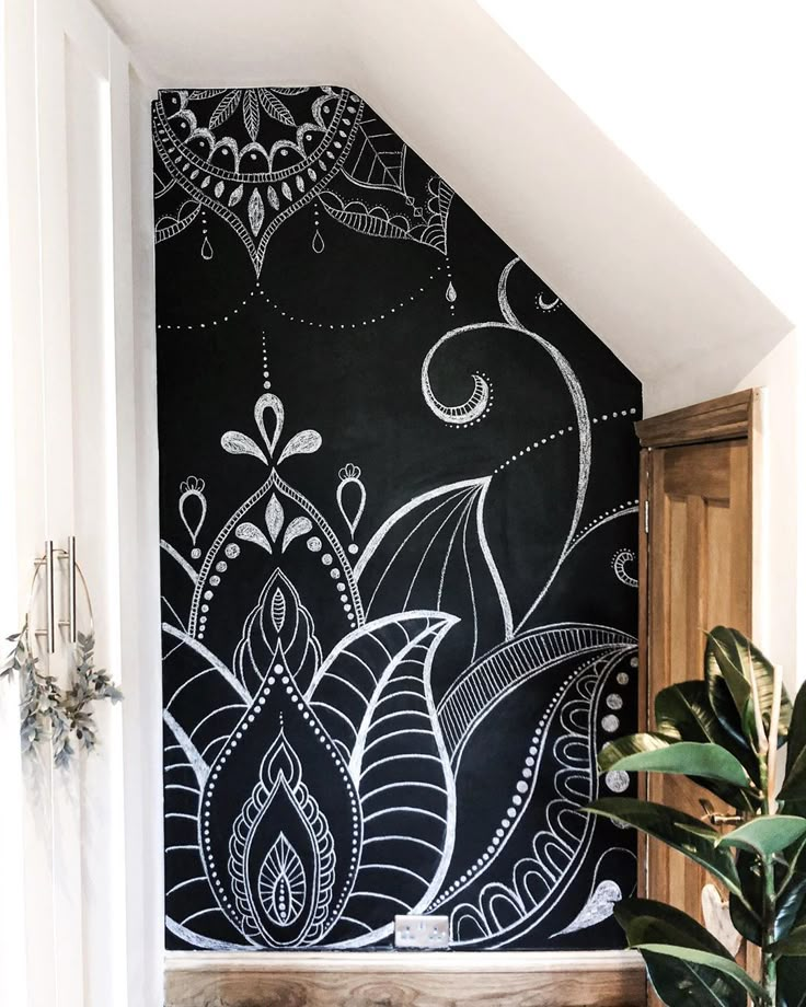 a black and white wall with an artistic design painted on it's side, next to a potted plant