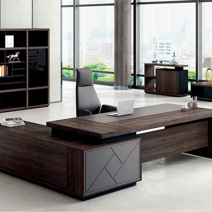 an office desk in the middle of a room with large windows and lots of bookshelves