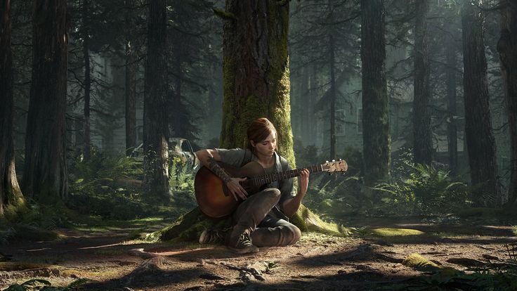 a man sitting on the ground playing an acoustic guitar next to a tree in a forest