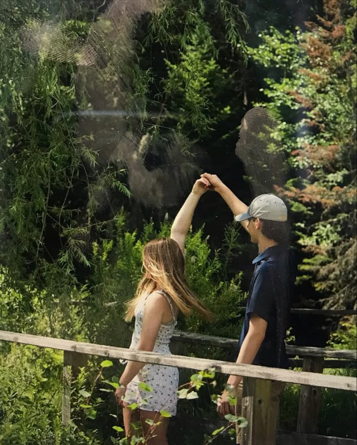 a man and woman standing on a bridge high up in the air with their hands together